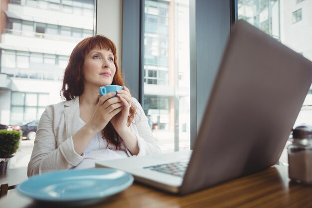 Donna di affari incinta che mangia caffè nella caffetteria