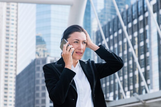 Donna di affari infelice che parla sul telefono cellulare in città