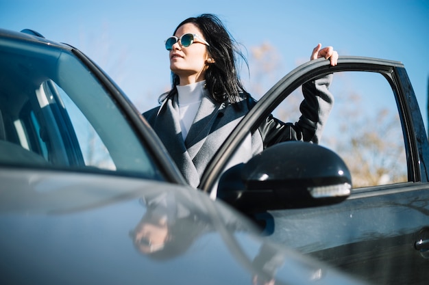 Donna di affari moderna che si leva in piedi vicino all&#39;automobile