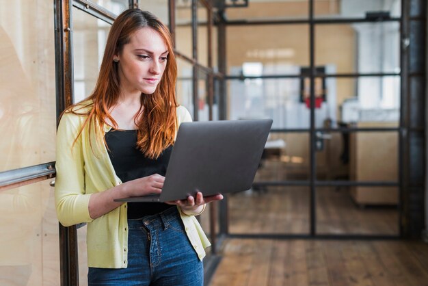 Donna di affari sicura che utilizza computer portatile nel luogo di lavoro