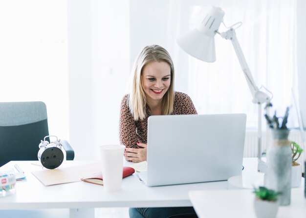 Donna di affari sorridente che esamina computer portatile