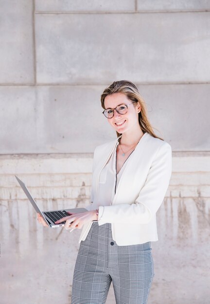 Donna di affari sorridente con il computer portatile sulla via