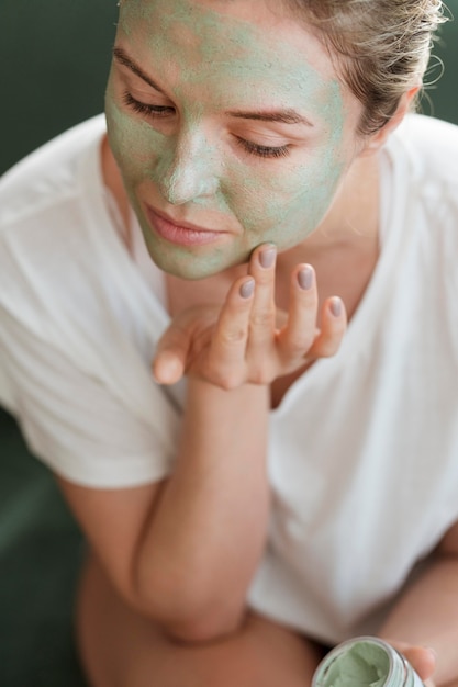 Donna di alta vista che applica maschera facciale all'interno