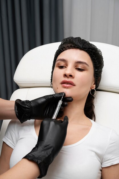 Donna di alto angolo che ottiene riempitivi per le labbra in clinica