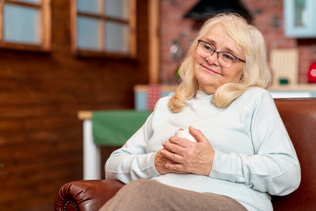 Donna di angolo basso a casa che beve tè