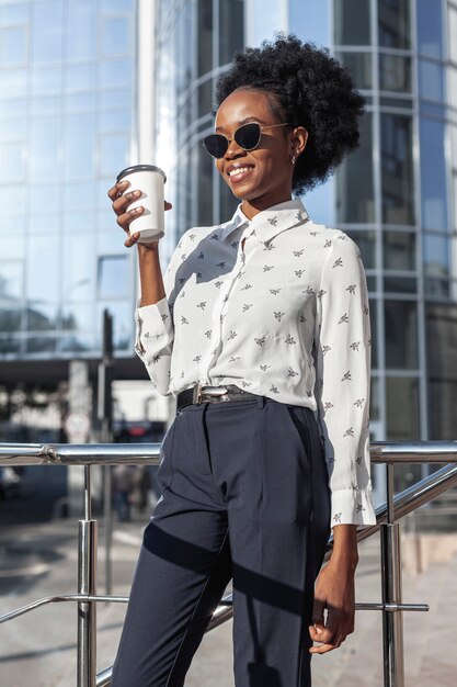 Donna di angolo basso al sole che beve caffè