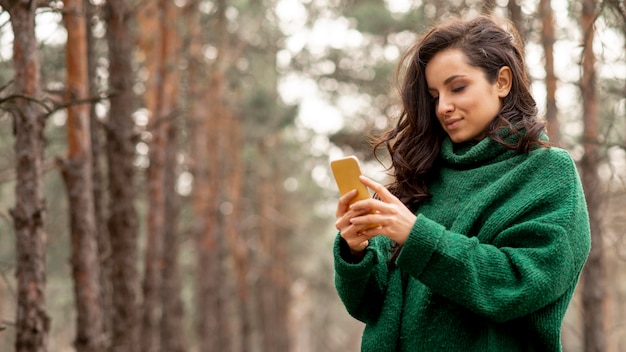 Donna di angolo basso che controlla cellulare