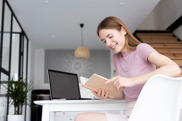 Donna di angolo basso che legge il suo libro