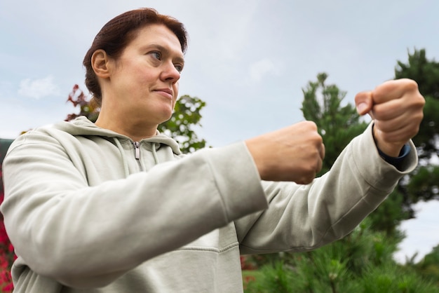 Donna di angolo basso che pratica il tai chi fuori