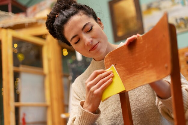 Donna di angolo basso che ripristina sedia di legno