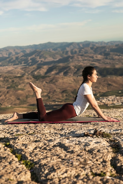 Donna di angolo basso sull'addestramento di yoga della stuoia