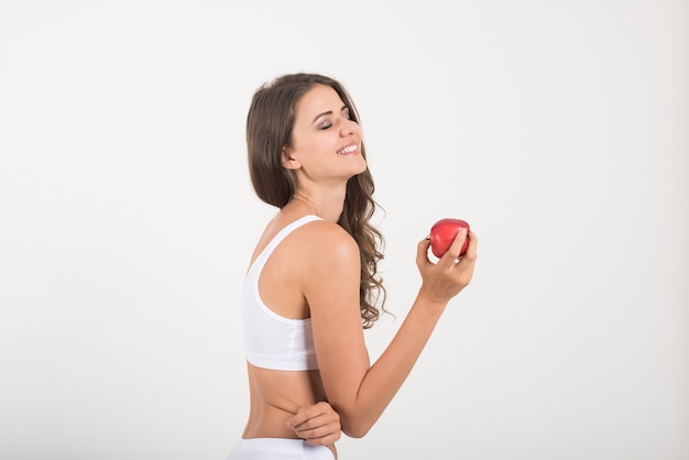 Donna di bellezza che tiene mela rossa mentre isolato su bianco