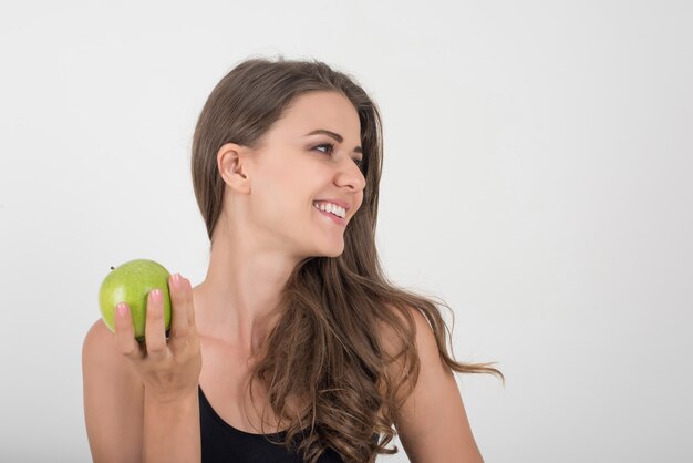 Donna di bellezza che tiene mela verde mentre isolato su bianco