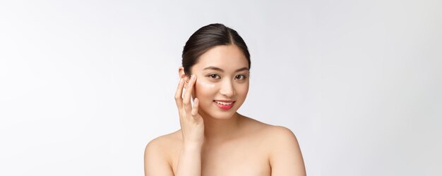 Donna di bellezza di cura della pelle Bellezza donna sorridente applicando crema Ritratto di bellezza del modello femminile caucasica asiatica bella isolata on white