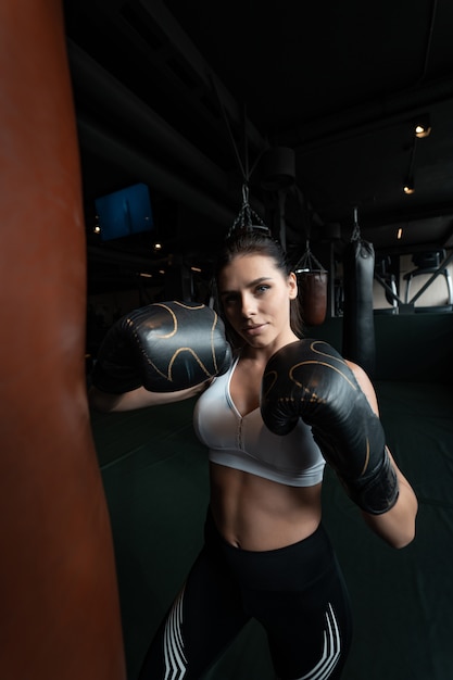 Donna di boxe in posa con il sacco da boxe. Concetto di donna forte e indipendente