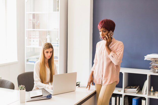 Donna di colore che parla sul telefono vicino al collega