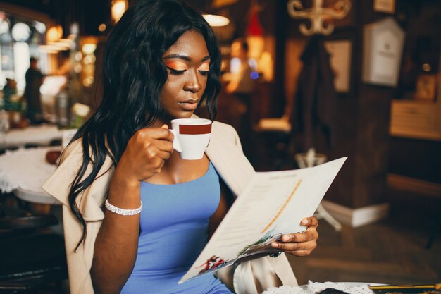 Donna di colore che si siede in un caffè