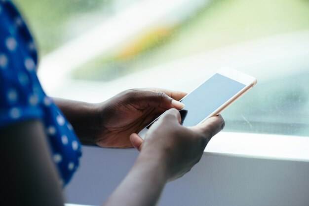 Donna di colore irriconoscibile che per mezzo dello smartphone