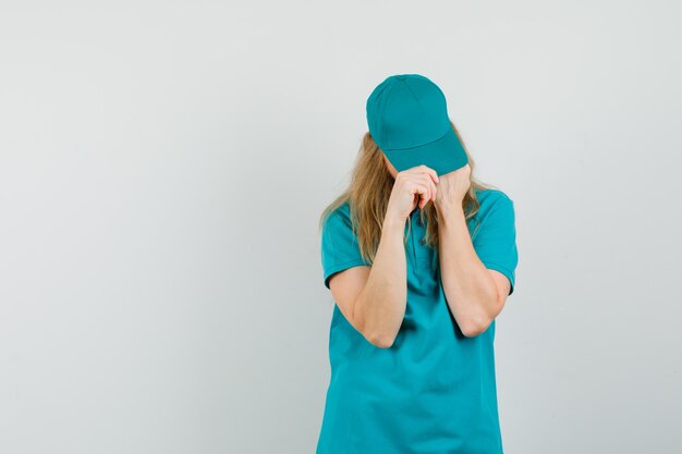 Donna di consegna che adegua il berretto in t-shirt, berretto e sembra in ordine.