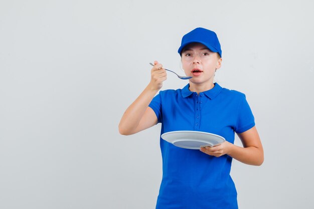 Donna di consegna che mangia con il cucchiaio in maglietta e cappuccio blu