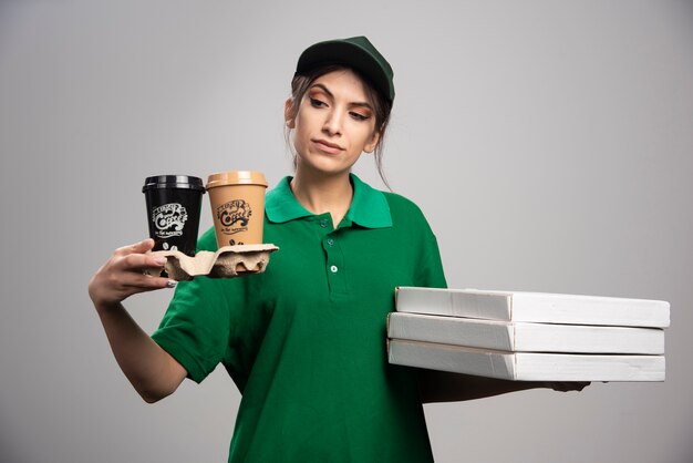 Donna di consegna che tiene tazze di caffè e scatole per pizza.