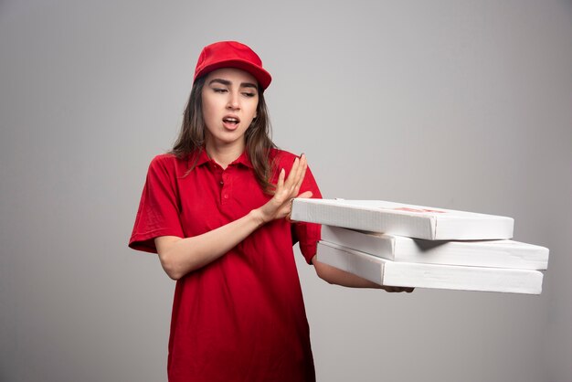 Donna di consegna in piedi lontano da scatole per pizza.