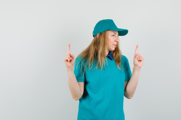 Donna di consegna rivolta verso l'alto mentre guarda da parte in t-shirt, berretto e sembra positiva.