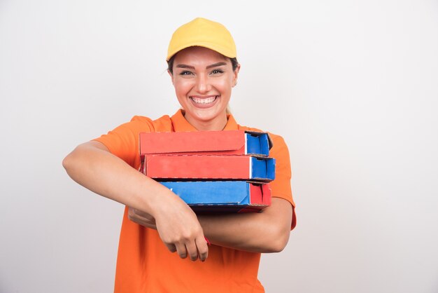 Donna di consegna sorridente che tiene scatole per pizza su uno spazio bianco