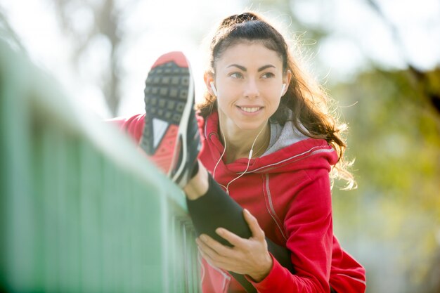 Donna di corridore felice facendo esercizi di stretching sul ponte