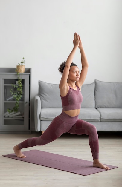 Donna di forma fisica che fa yoga su una stuoia di yoga a casa