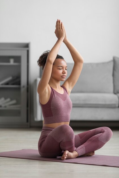 Donna di forma fisica che fa yoga su una stuoia di yoga a casa