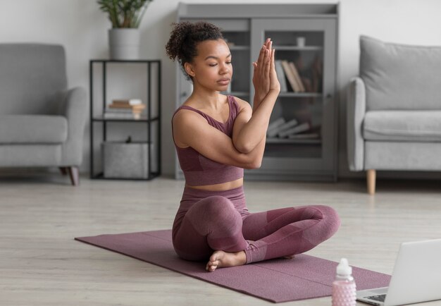 Donna di forma fisica che fa yoga su una stuoia di yoga a casa