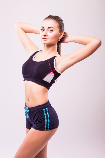 Donna di forma fisica. Giovane modello femminile caucasico sportivo isolato su priorità bassa bianca in tutto il corpo