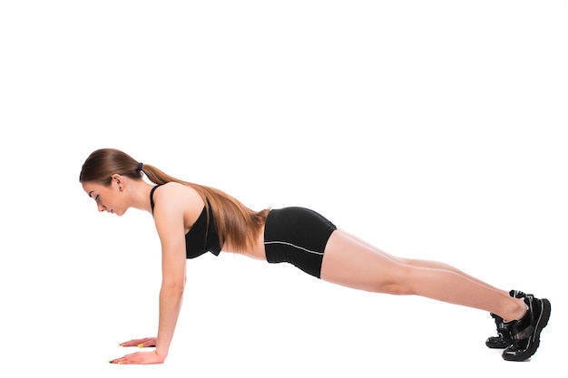Donna di forma fisica sulla postura di base della plancia di allenamento degli addominali su priorità bassa bianca