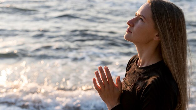 Donna di lato meditando sulla spiaggia