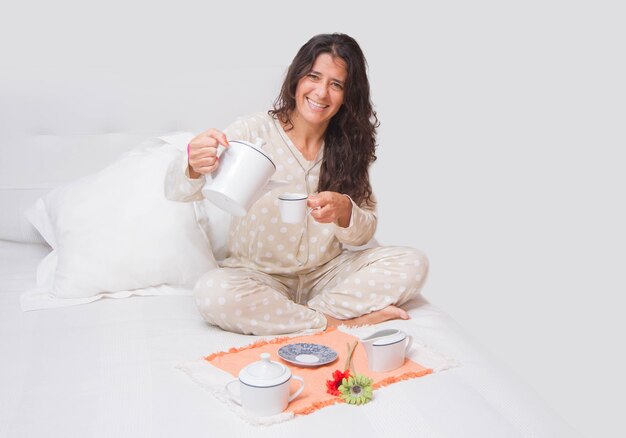 Donna di mezza età allegra che fa colazione a letto