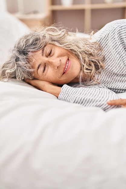 Donna di mezza età sdraiata sul letto che dorme in camera da letto