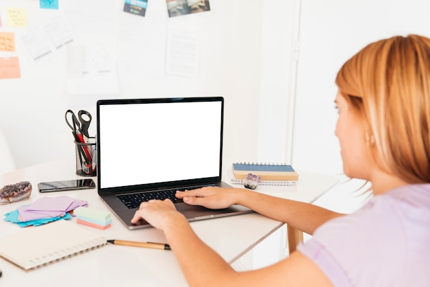 Donna di redhead che digita sul computer portatile allo scrittorio con cartoleria