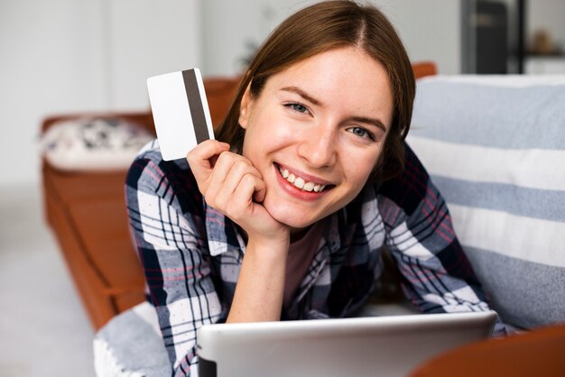 Donna di smiley che esamina la macchina fotografica e che tiene una carta di credito