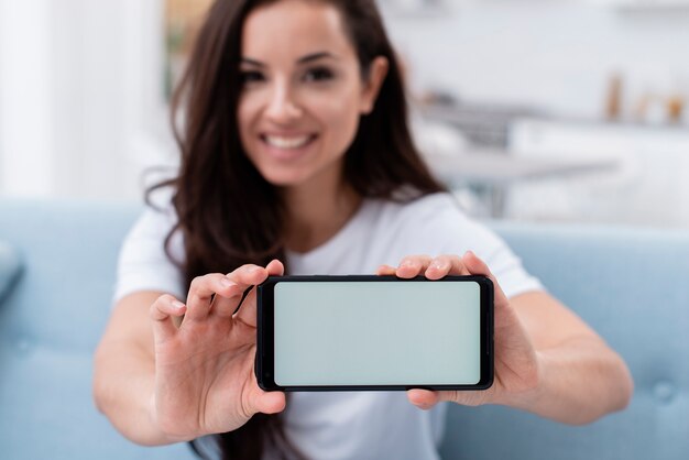 Donna di smiley che mostra il suo telefono vuoto dell'esposizione