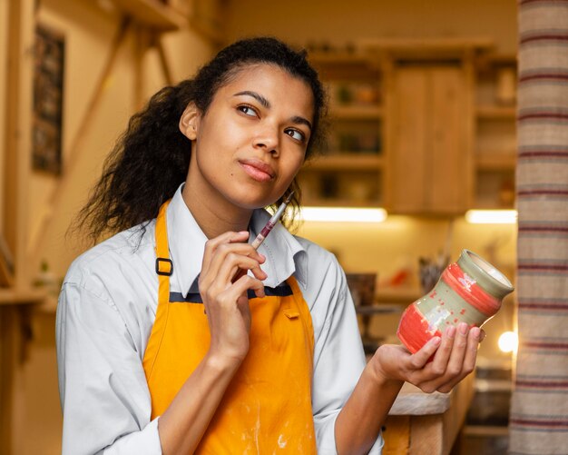 Donna di smiley che pensa con la pentola di terracotta