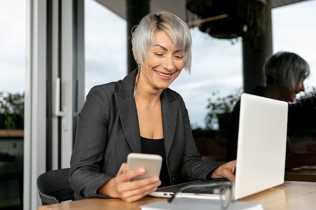 Donna di smiley che per mezzo di dispositivi elettronici