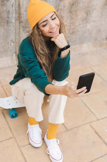 Donna di smiley che prende selfie mentre sedendosi sul pattino