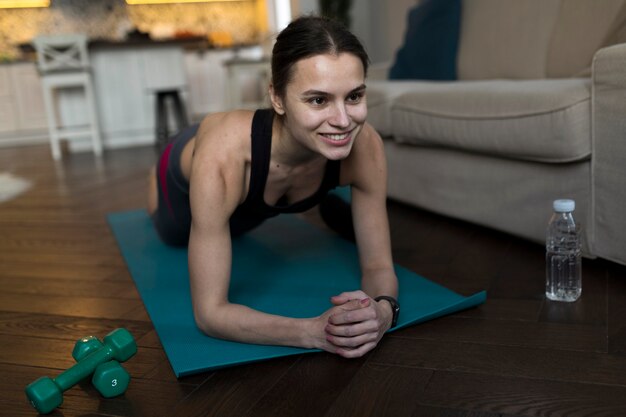 Donna di smiley che si esercita sulla stuoia di yoga