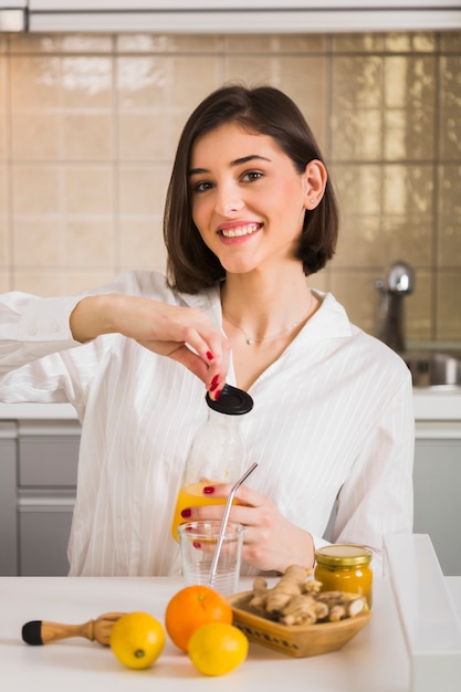 Donna di smiley che tiene il succo di arancia fatto in casa