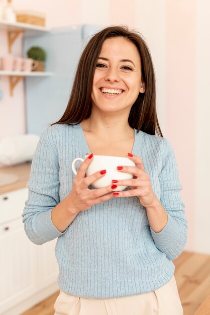 Donna di smiley del colpo medio che propone con la tazza