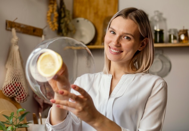 Donna di smiley del colpo medio che pulisce con il limone