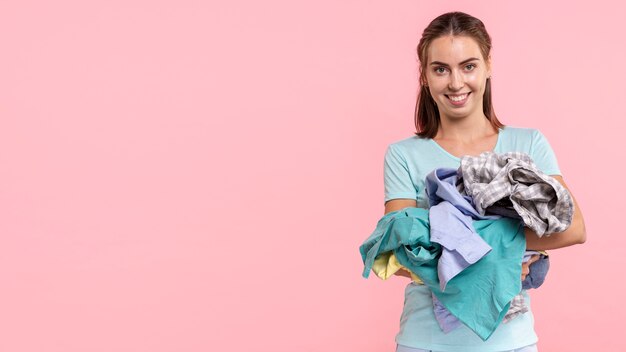 Donna di smiley del colpo medio che trasporta i vestiti