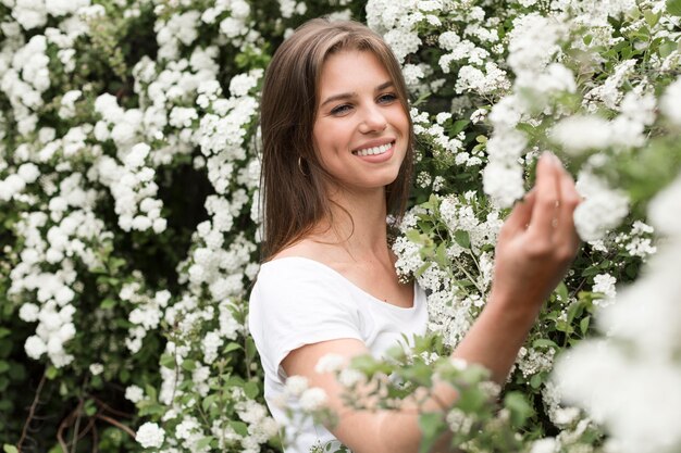 Donna di smiley del ritratto che esamina i fiori