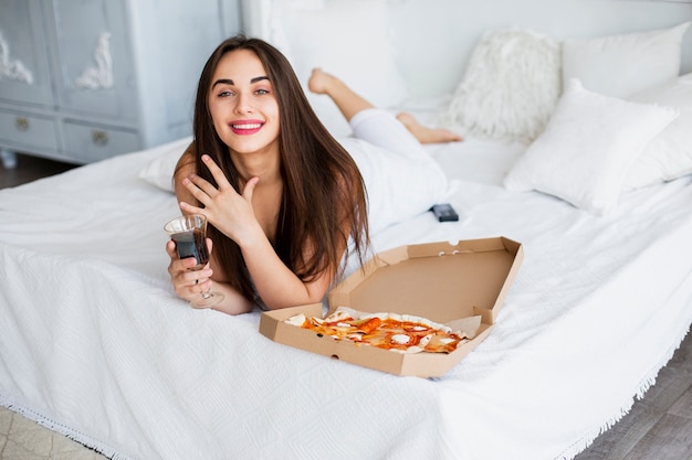 Donna di smiley dell'angolo alto che mangia pizza